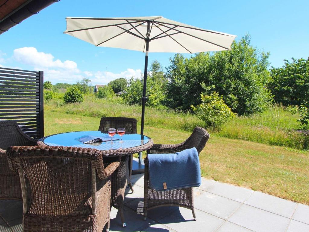 a table and chairs with an umbrella on a patio at 4 person holiday home in R nne in Rønne