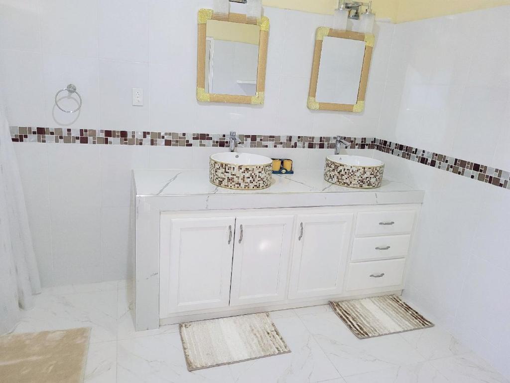 ein Bad mit 2 Waschbecken und Spiegeln an der Wand in der Unterkunft Jay's Chill Paradise in Yallahs