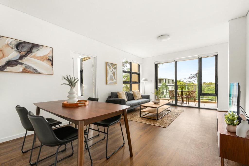 un soggiorno con tavolo, sedie e divano di Stylish 2-Bed, 2-Bath with Parking in Lane Cove a Sydney