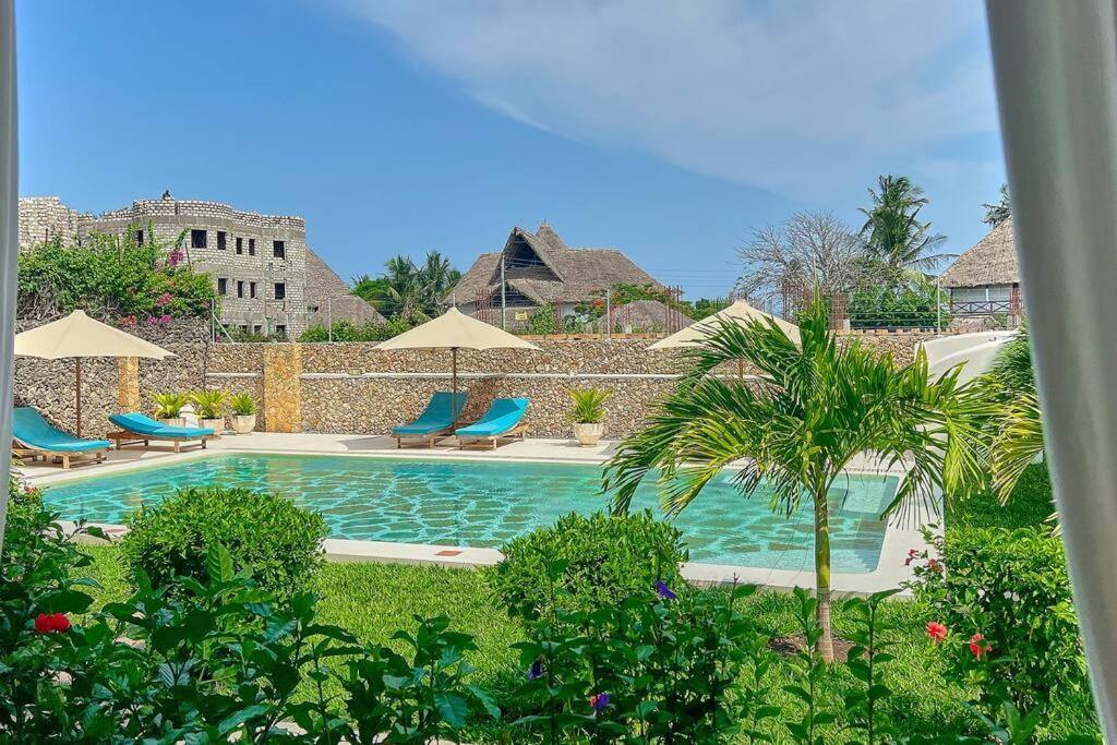 a swimming pool with chairs and umbrellas at Beach Apartment 4 Passi Residence in Watamu