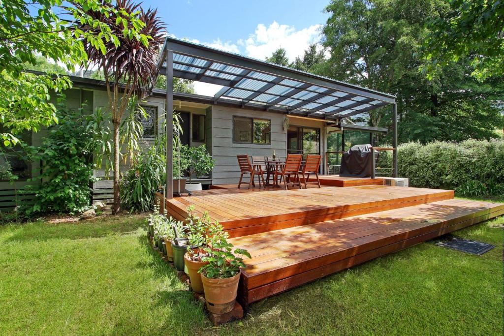 a deck with a table and chairs in a backyard at Rail Trail Cottage - Bright in Bright