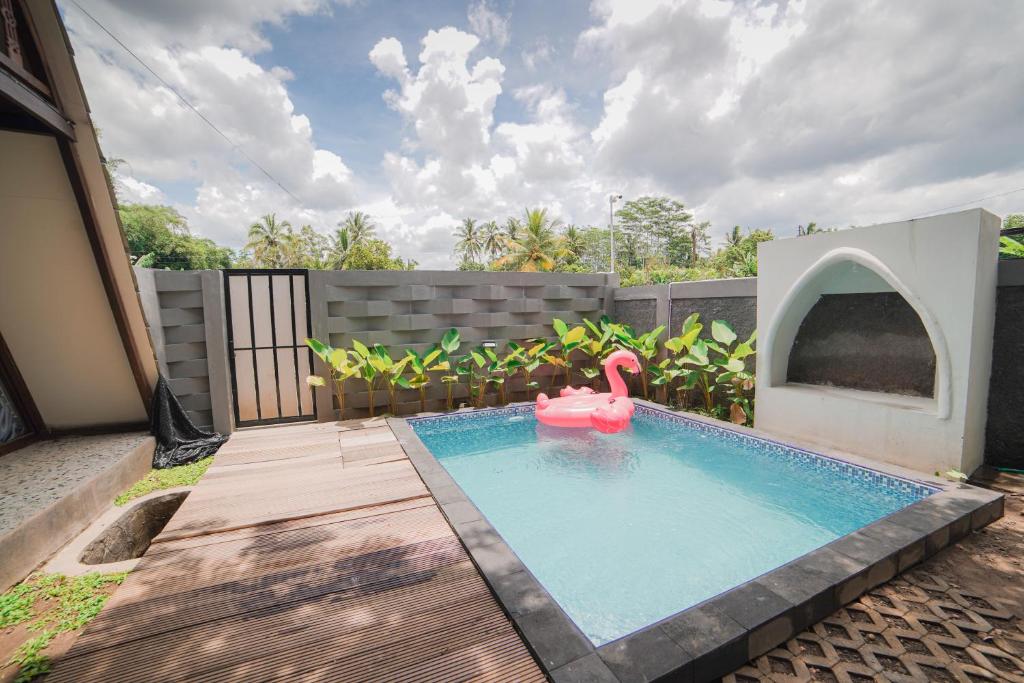 a swimming pool with a pink swan in a backyard at Ubu Villa Kinanthi in Bedoyo