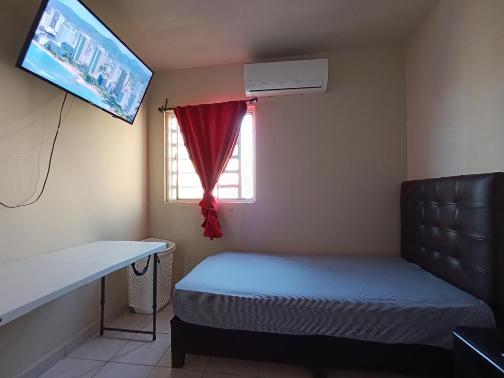 um pequeno quarto com uma cama e uma janela em Confortable habitación em Colonia Alamitos