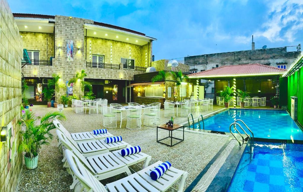 a patio with white lounge chairs and a pool at Hotel Grand Bhagwat, Udaipur in Udaipur