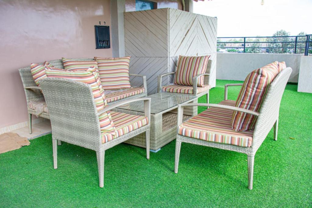 a table and chairs on a balcony with green grass at Kigoma Suites in Nyahururu