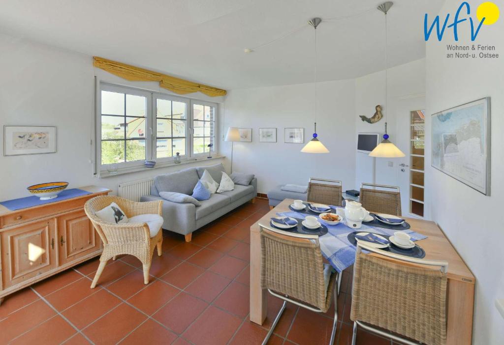 ein Wohnzimmer mit einem Tisch, Stühlen und einem Sofa in der Unterkunft Luv und Lee Ferienwohnung Dornbusch in Juist