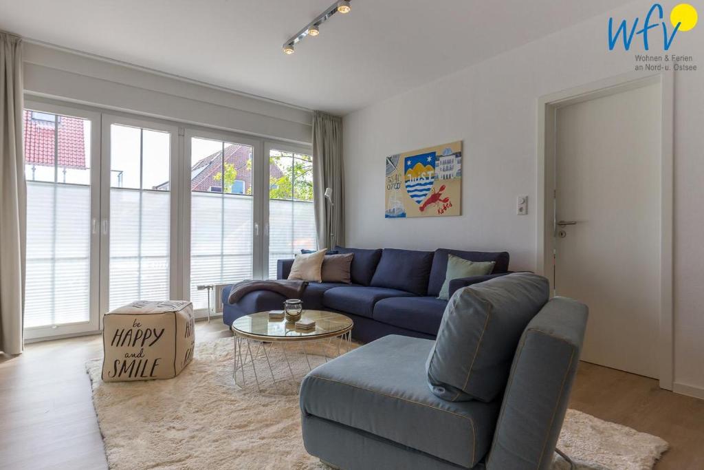 a living room with a blue couch and a table at Juist Zauber - Haus 3 Ferienwohnung Strandaster in Juist