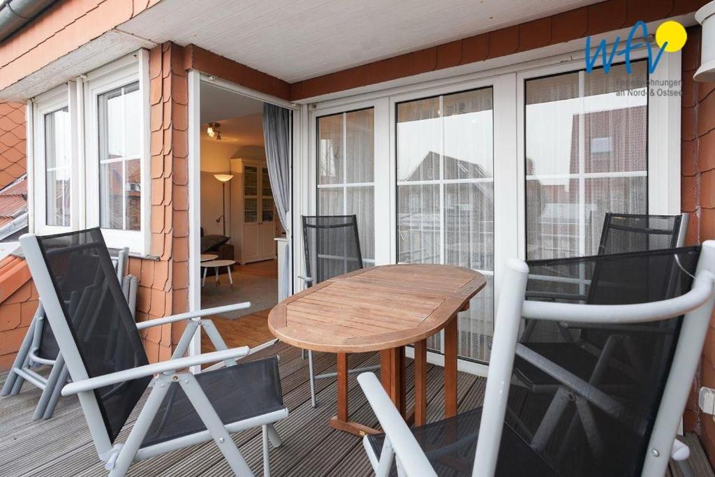 een veranda met een houten tafel en stoelen op een balkon bij Juist Zauber - Haus 3 Ferienwohnung Ockjes Stuuv in Juist