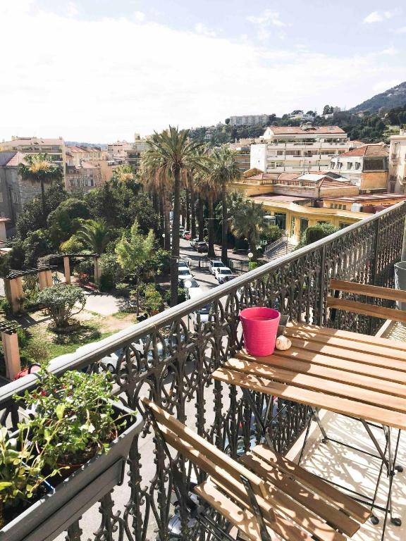 balcón con mesa de madera, sillas y palmeras en Charming Studio In The Heart Of Menton, en Menton