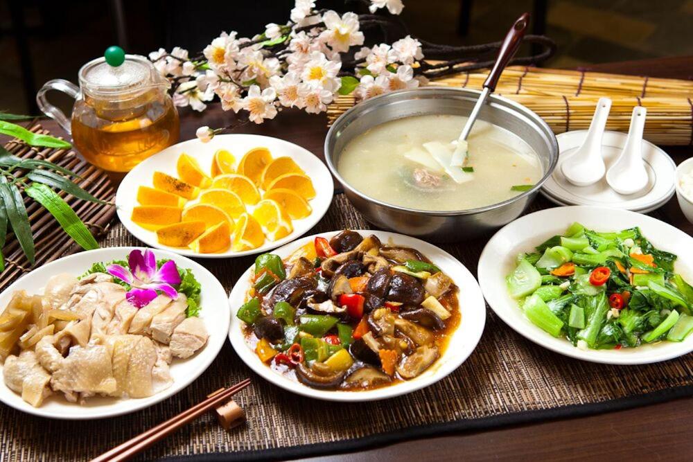 a table with plates of food and a bowl of soup at Shante Hotel Shitou in Lugu Lake