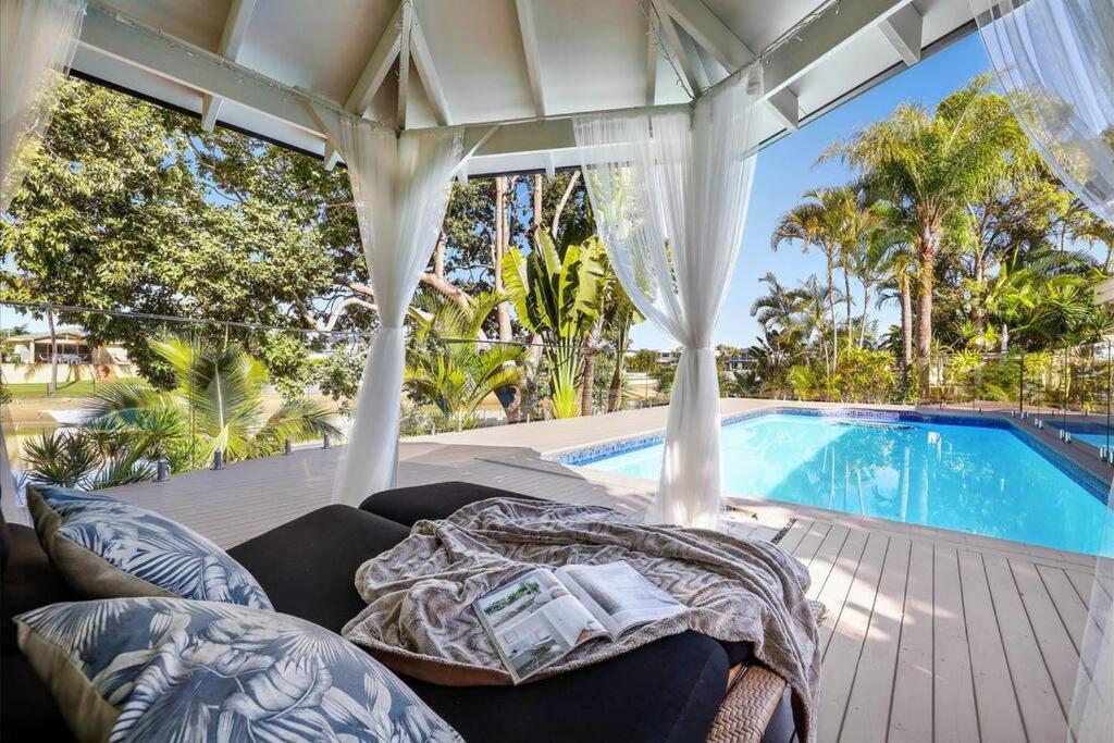 a patio with a couch and a swimming pool at Waterfront Escape Sorrento, 5BD- Pool in Gold Coast