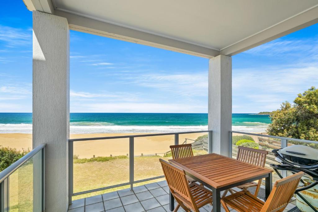 a balcony with a table and chairs and a view of the beach at Seaside Symphony, Sleep and Wake to Ocean Waves in Wamberal