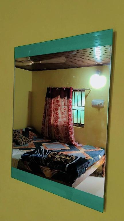 a mirror reflecting a bed in a room at Deepu Guest house in Gokarna