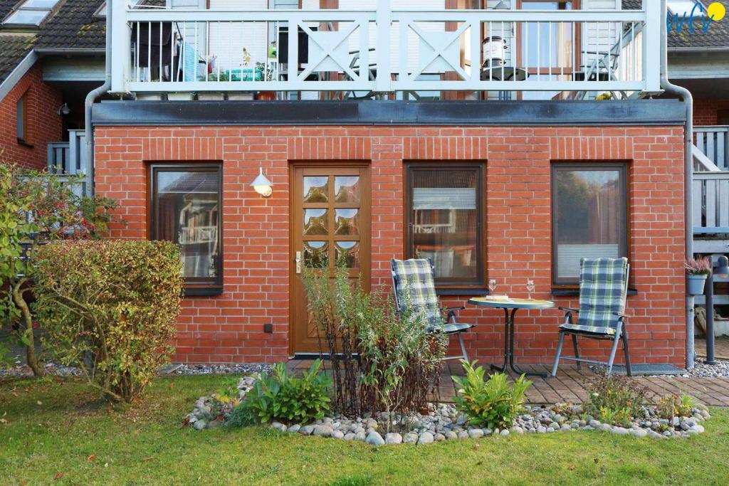 ein rotes Backsteinhaus mit 2 Stühlen und einem Balkon in der Unterkunft Ferienpark Seedorf Fischerhaus - Ferienwohnung 8 in Sellin