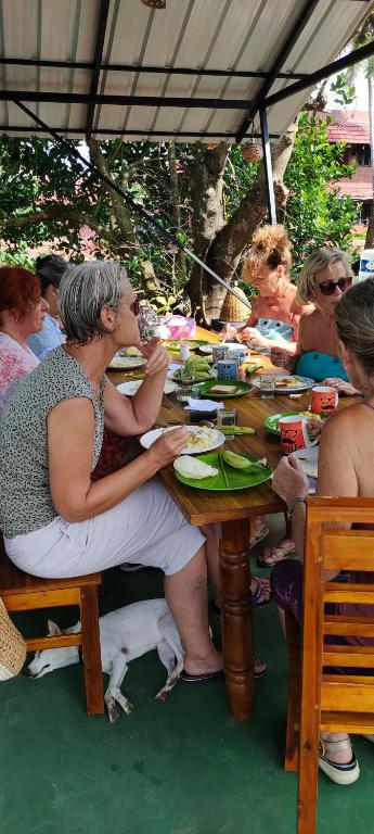 a group of people sitting at a table with a dog at Agasthya in Varkala