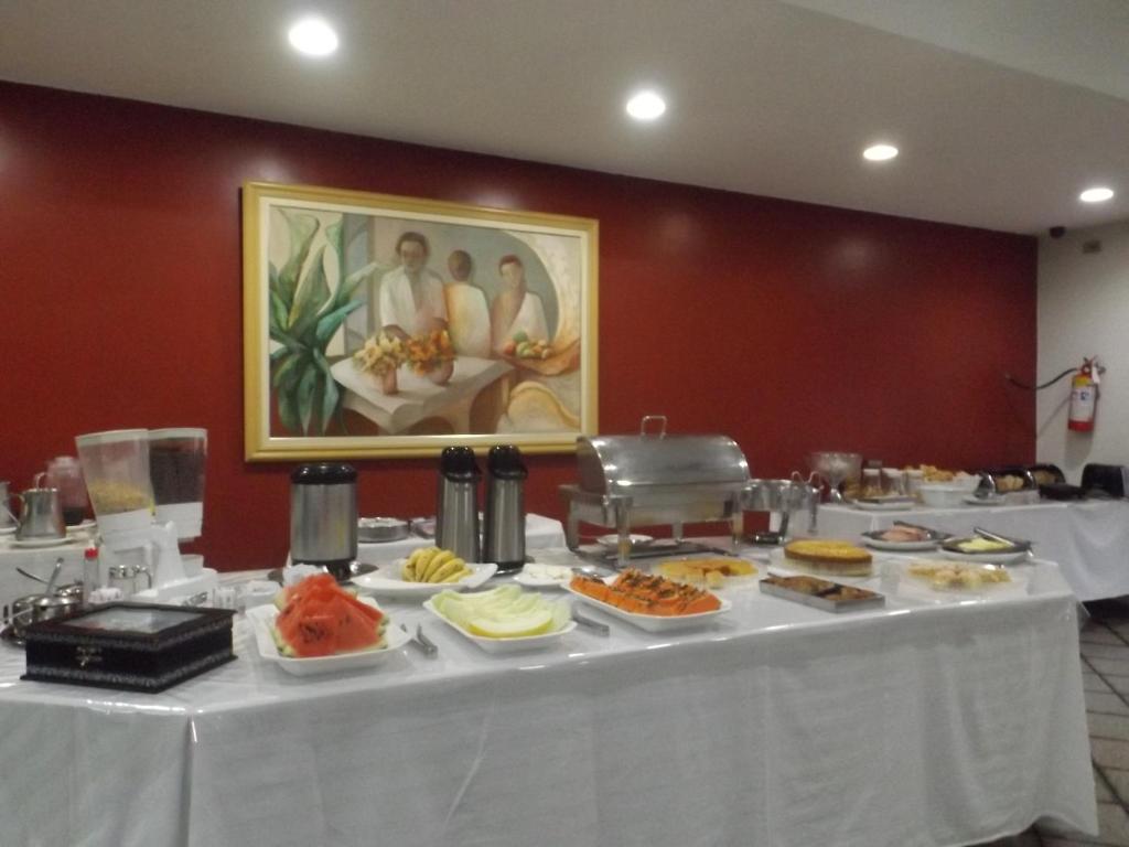 a table with plates of food on top at Martha Office Hotel in Bauru
