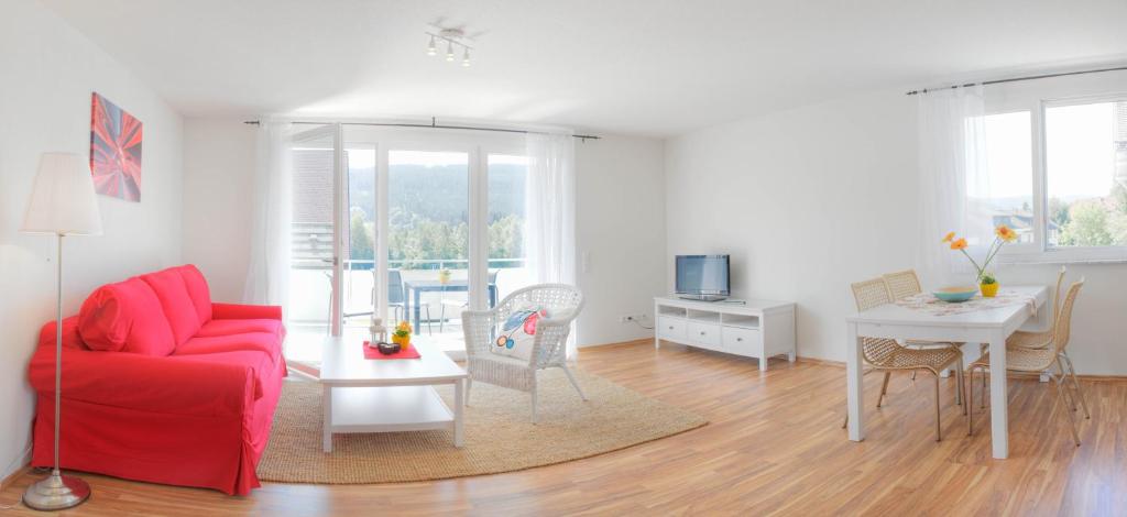 ein Wohnzimmer mit einem roten Sofa und einem Tisch in der Unterkunft Braviscasa - Ferienresidenz Hochfirst Titisee in Titisee-Neustadt