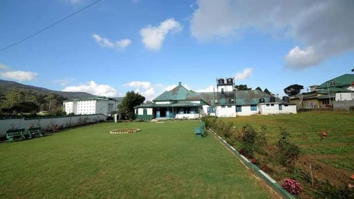 a large yard with a house and a field of grass at Country cottage in Nuwara Eliya