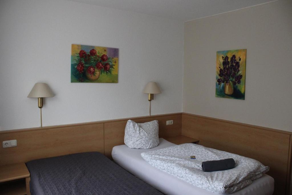 タウバービショフスハイムにあるLandhotel Garni am Mühlenwörthのベッド2台が備わる客室で、壁には絵画が飾られています。