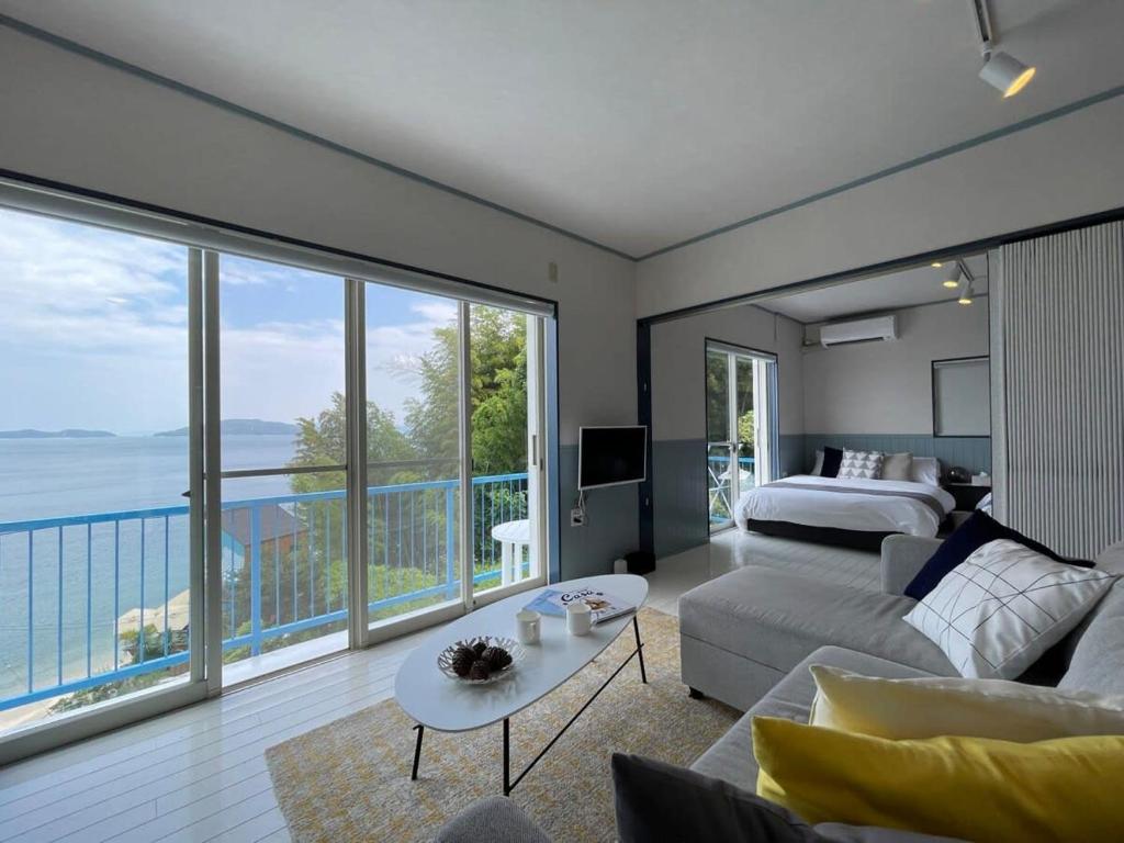 ein Schlafzimmer mit einem Bett und ein Wohnzimmer mit Aussicht in der Unterkunft bLOCAL AO house - 1 BR House with Ocean View Few min walk to the beach in Suo Oshima