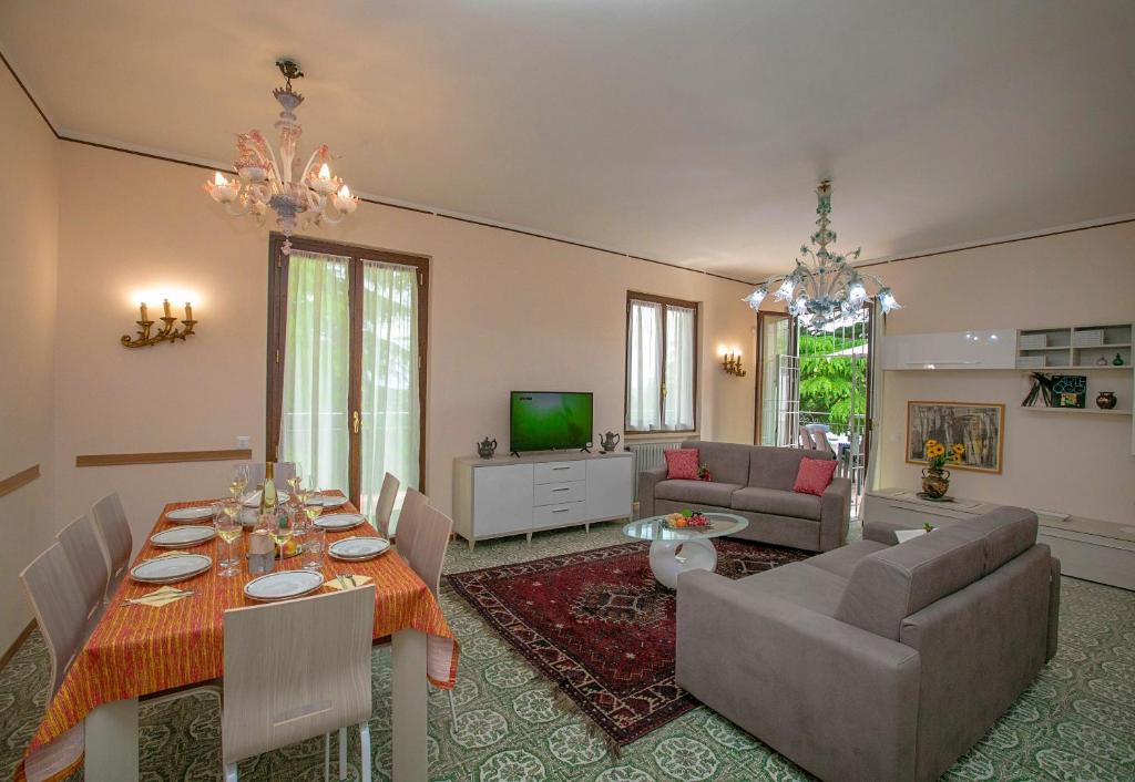 uma sala de estar com uma mesa, um sofá e uma televisão em Villa Alberti 900m from Garda lake - Happy Rentals em Salò