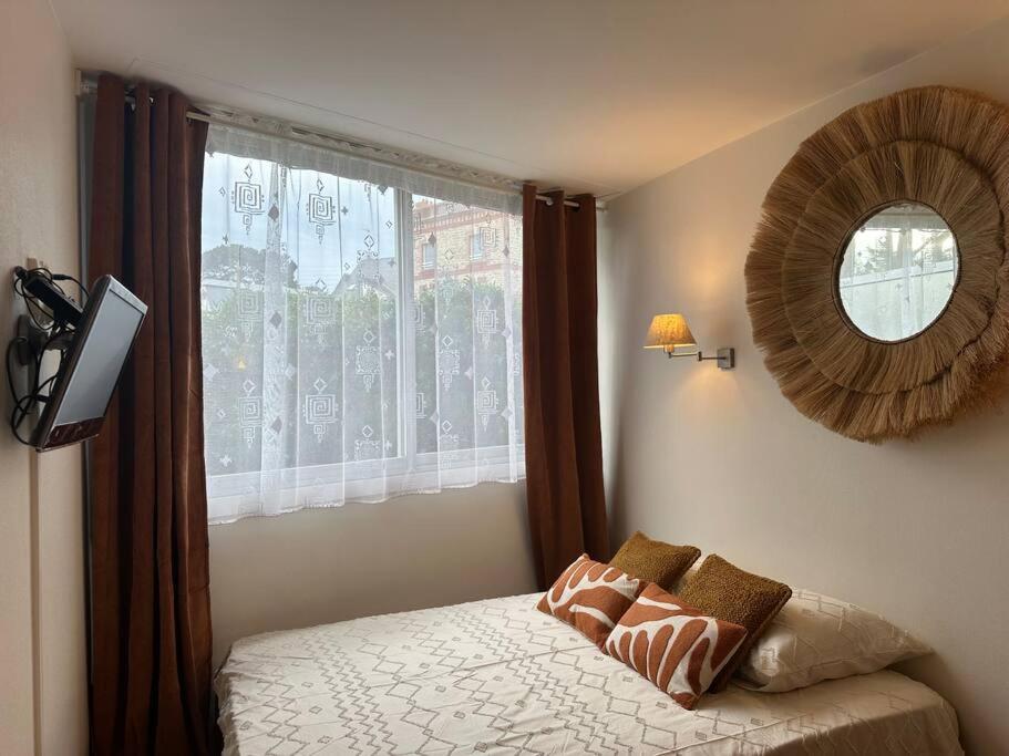 Schlafzimmer mit einem Bett mit einem Spiegel und einem Fenster in der Unterkunft Studio avec accès plage et mer in Dinard