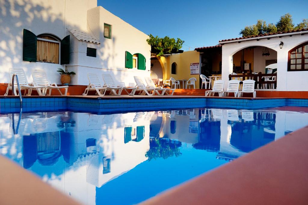 a swimming pool in front of a house with chairs at Elia & Tina Apartments in Hersonissos