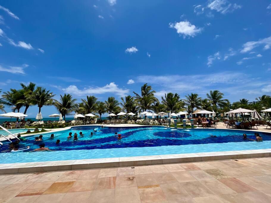 uma piscina num resort com pessoas em Seu cantinho no paraíso de Guarajuba - Bahia em Guarajuba