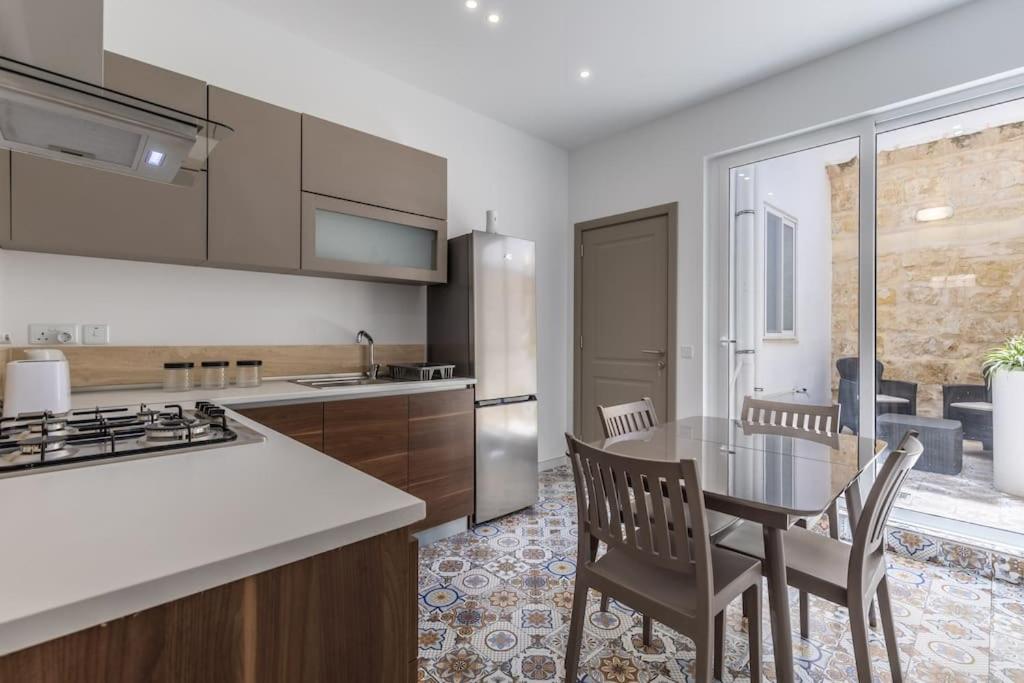 a kitchen with a table and chairs and a kitchen with a counter at Town House in the Heart of Luqa - close to Malta International Airport in Luqa