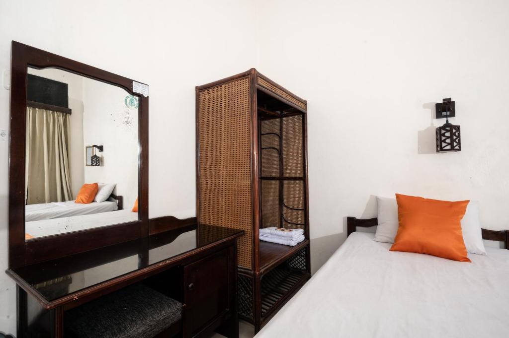 een slaapkamer met een spiegel en een bed bij Oryza Hotel Malioboro in Sentool