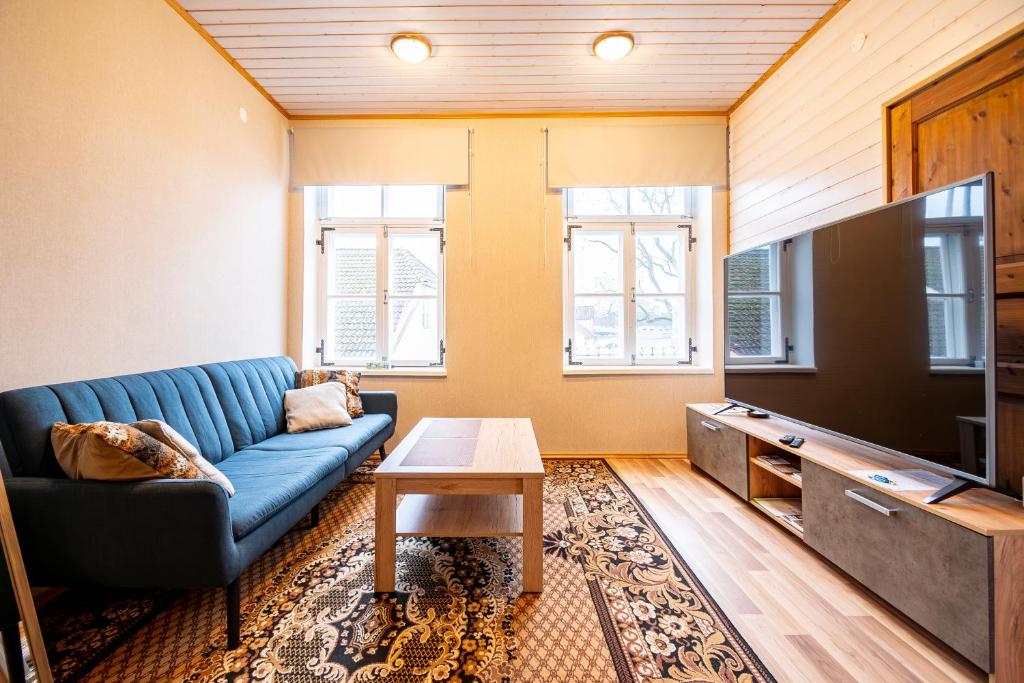 a living room with a blue couch and a flat screen tv at Kauba 6-6 Apartment in Kuressaare