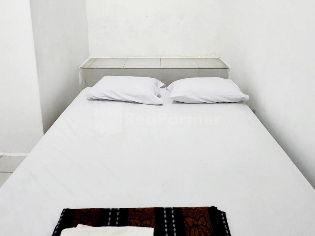 uma cama branca com duas almofadas em cima em Hotel California Mitra RedDoorz em Pembunuh