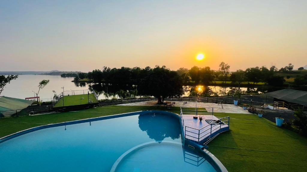 una piscina con puesta de sol en el fondo en Amigos Lake Resort-Igatpuri, en Igatpuri