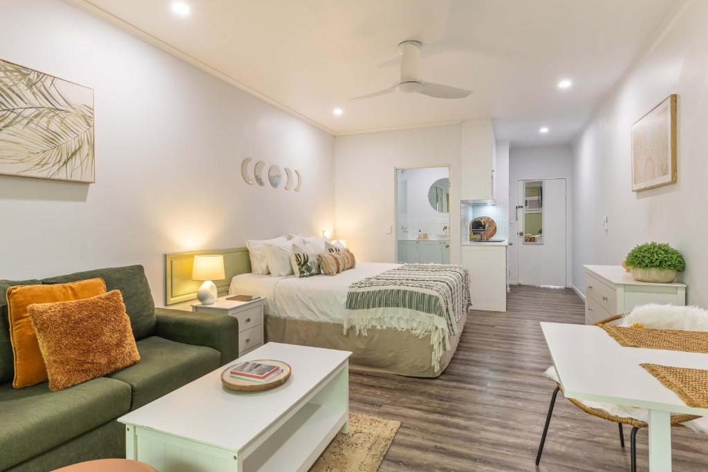 a bedroom with a bed and a couch and a table at Tropic Retreat in Port Douglas