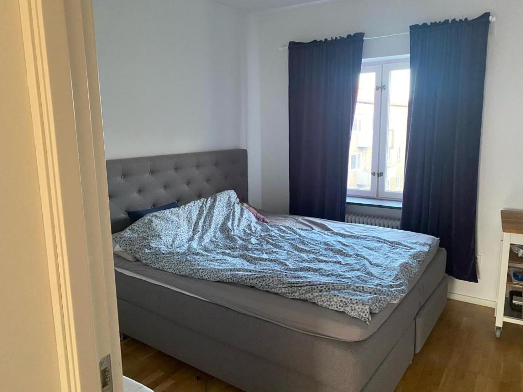 a bed in a bedroom with blue curtains at Eurovision Finale 1BD in Malmö