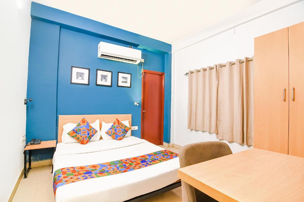 a blue room with a bed and a table at FabExpress P3 in Ballygunge