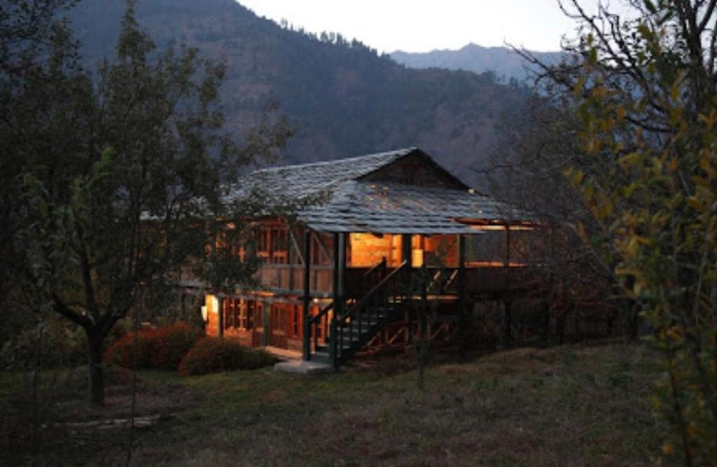 a large wooden house with a staircase in a field at Woodside Traditional Homestays in Nagar