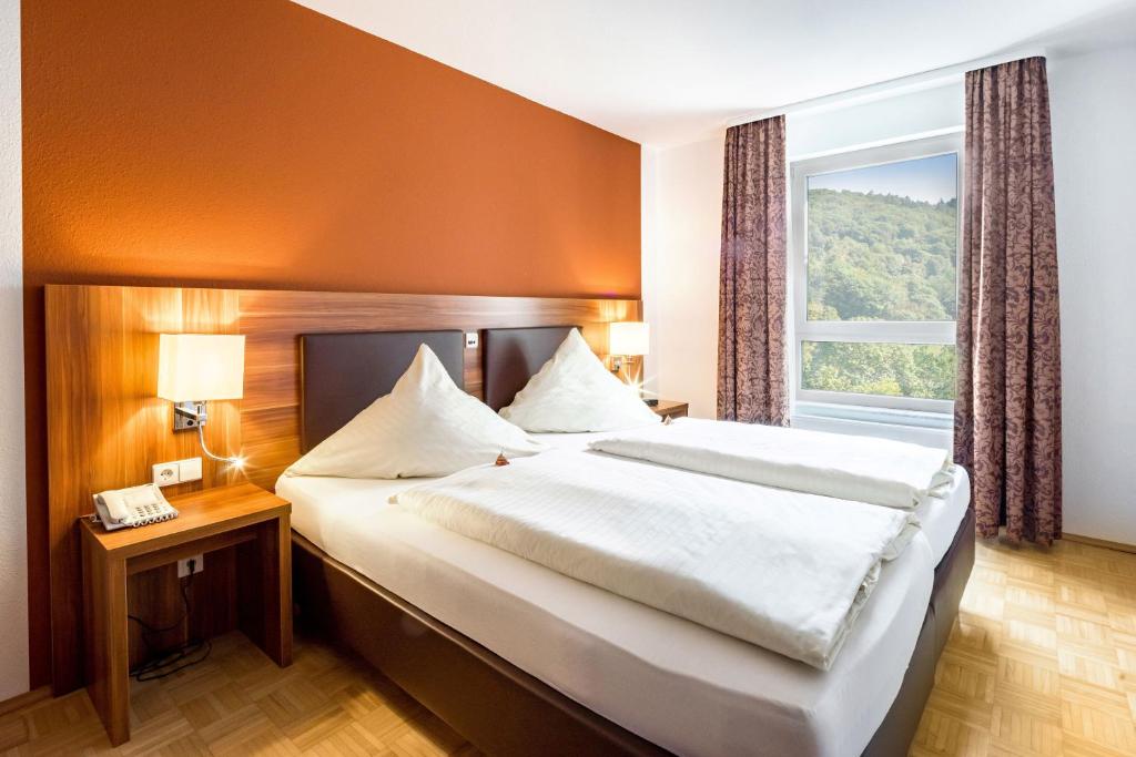 Un dormitorio con una cama grande y una ventana en Hotel & Residenz Am Kurpark en Schlangenbad