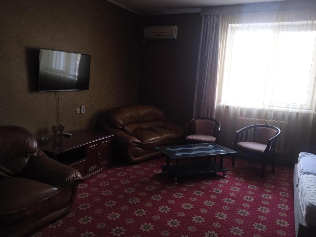 sala de estar con muebles de cuero y TV en ОРДА en Shymkent