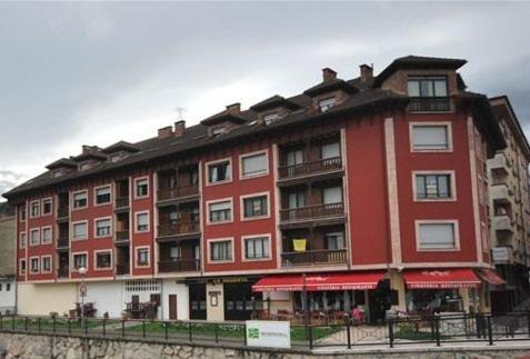 un gran edificio de apartamentos rojo con una valla delante en Pension Paseo Real, en Cangas de Onís