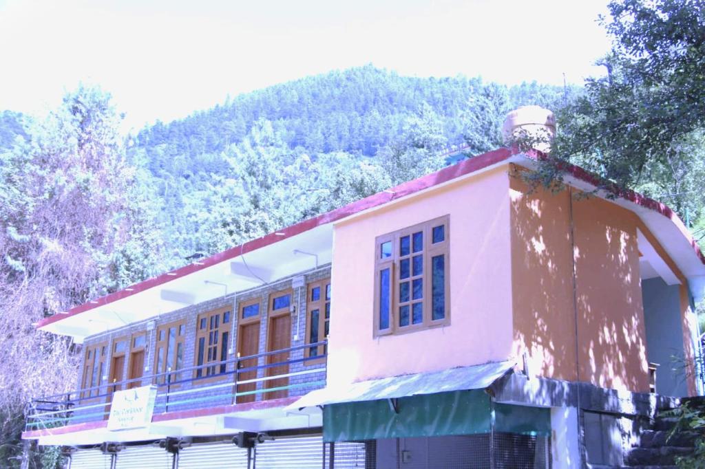 um edifício cor-de-rosa com uma montanha ao fundo em Corridor Homestay em Sainj