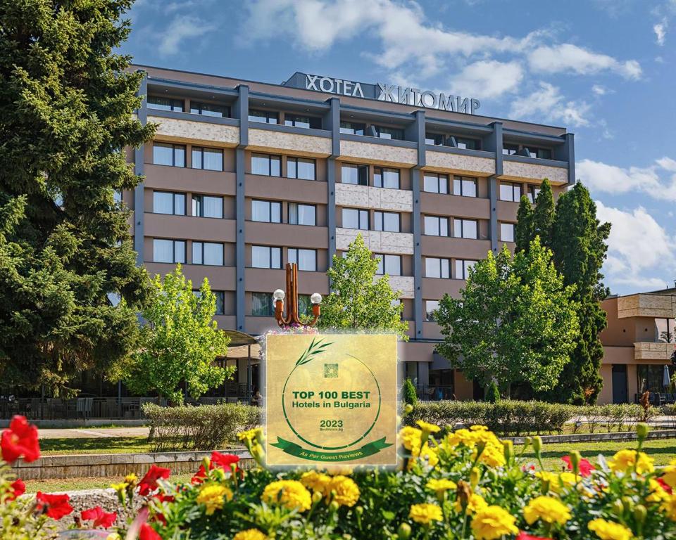 un panneau devant un hôtel avec des fleurs dans l'établissement Hotel complex Jitomir, à Montana