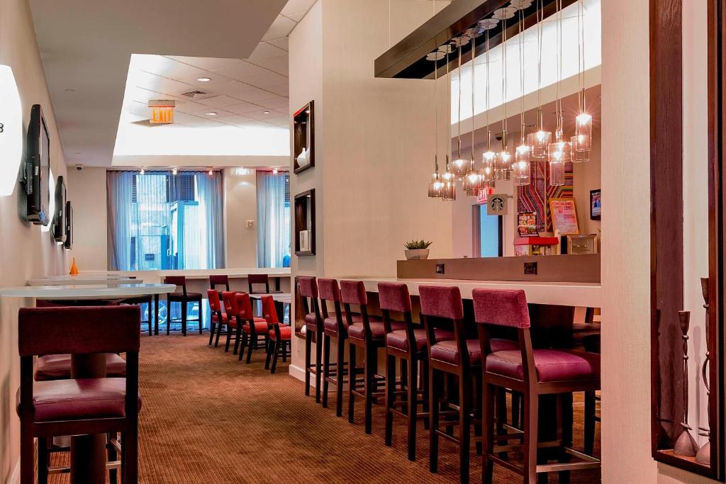 un restaurant avec un bar et des chaises rouges dans l'établissement Courtyard New York Manhattan/Times Square, à New York