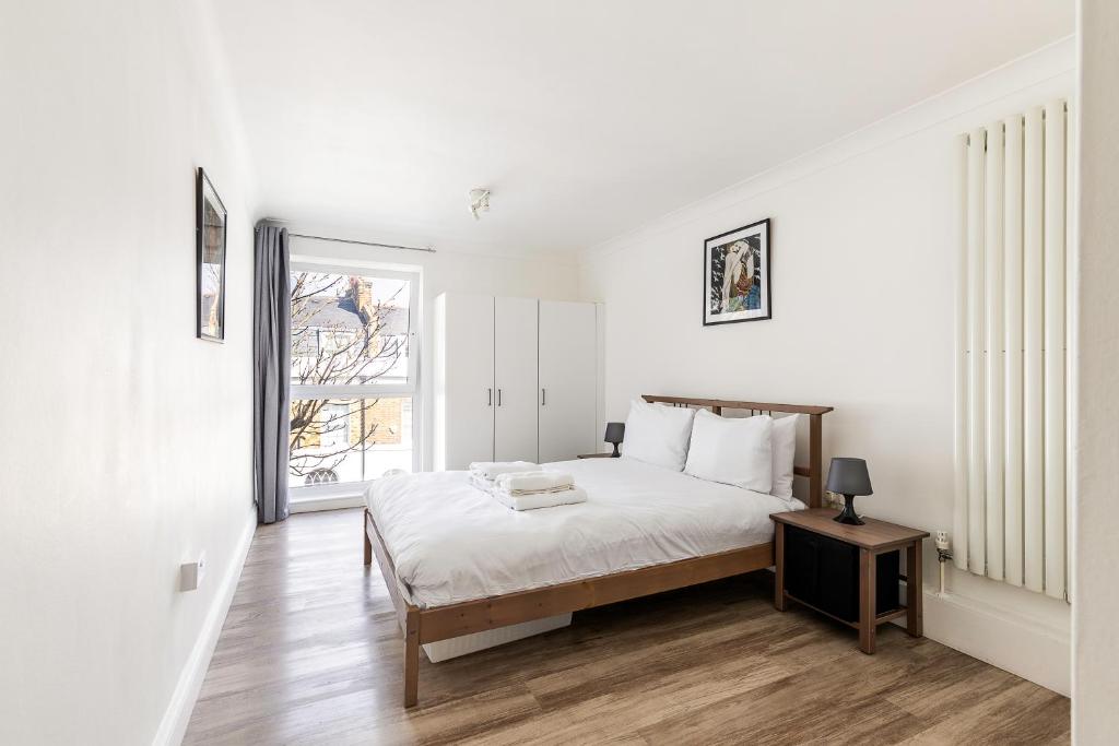 a white bedroom with a bed and a window at Cosy Angel Flat Tube Nearby Stunning Views! in London