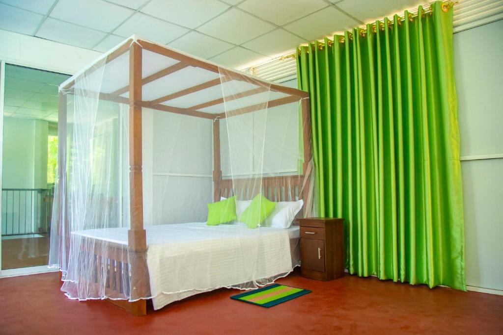 um quarto com uma cama de dossel e cortinas verdes em Green View Lodge em Deniyaya