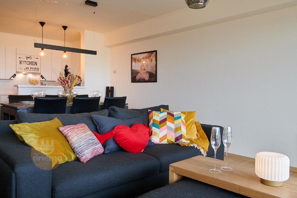 uma sala de estar com um sofá azul com almofadas coloridas em DUIN 0503 - Appartement voor 8 personen em De Panne