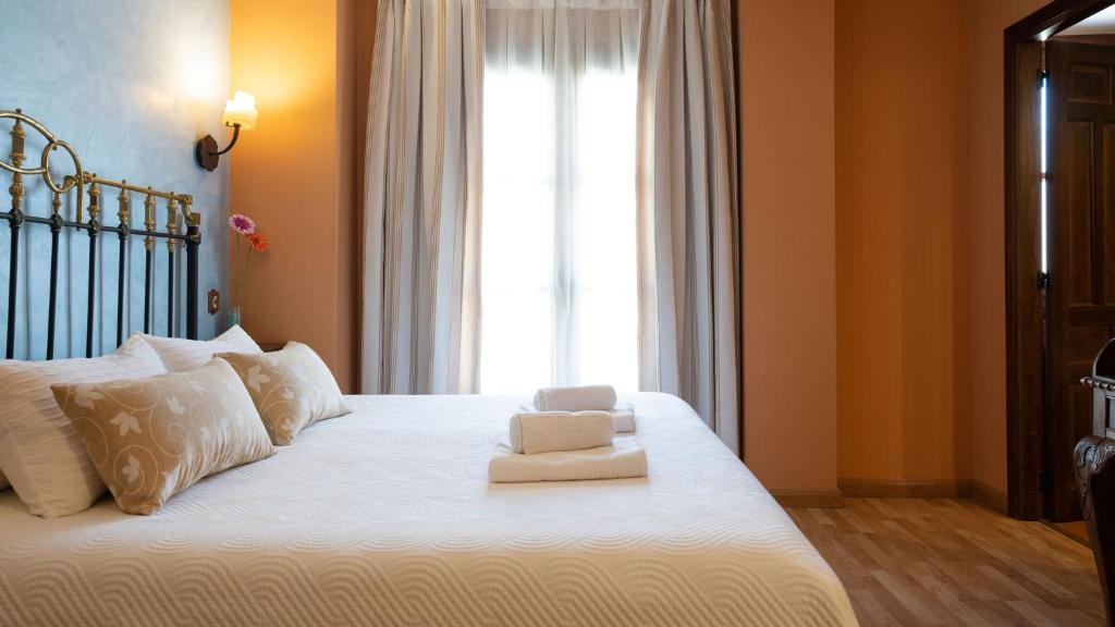 a bedroom with a large white bed with a window at Hospederia Princesa Elima in Brihuega