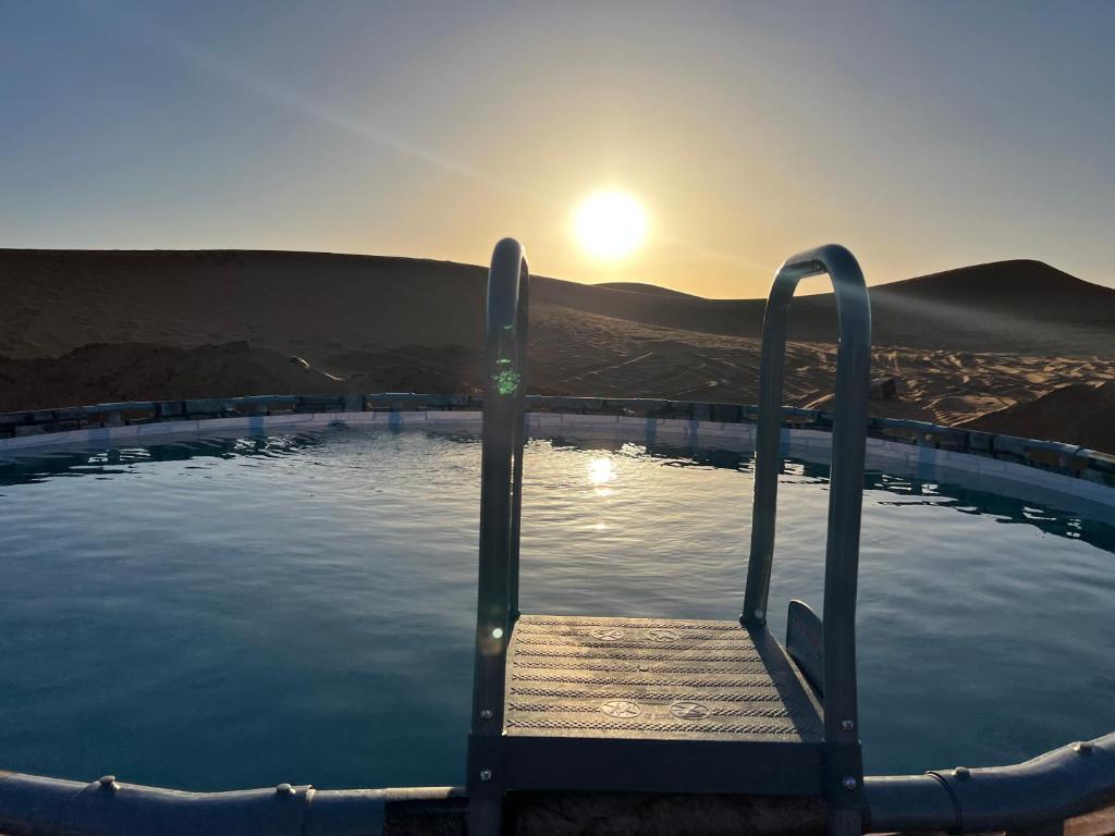 a plunge pool with a wooden bench in the water at Sahara Majestic Luxury Camp in Merzouga