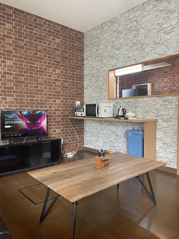 a living room with a wooden table with a tv at 巴ドットcom Premium Stay in Hakodate