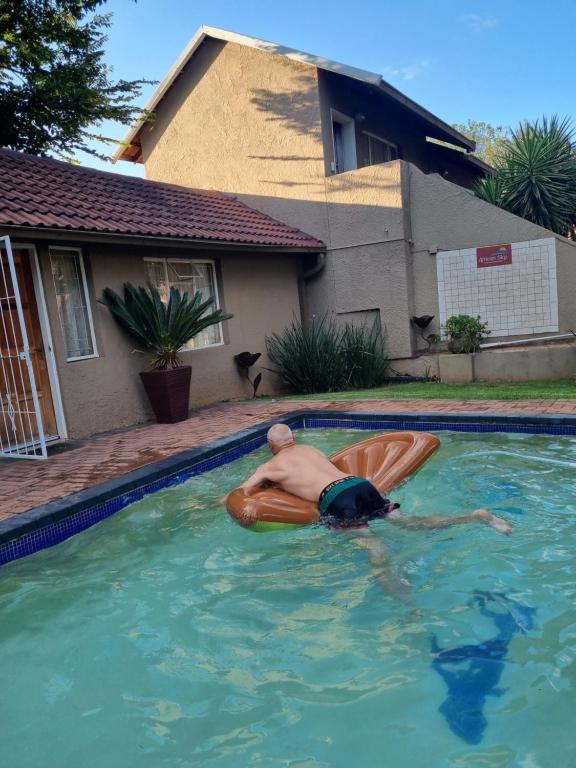 a man laying on a raft in a swimming pool at African Sky Guest House in Krugersdorp